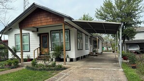 A single-story house with a covered porch, a front door, and a small front yard with potted plants.