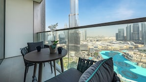 A balcony with a table, chairs, and a view of the Burj Khalifa. - Stunning Burj Khalifa & Fountain Views (Dubai)