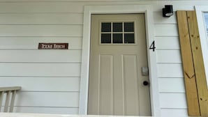 Una puerta blanca con un ventanal encima, el número 4 a la derecha y un letrero que dice 'Texas Ranch' sobre la puerta.