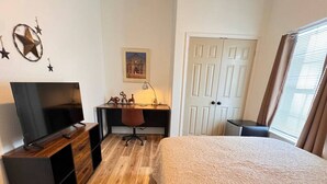 Una habitación de hotel con una cama, un escritorio con computadora, televisor y una silla.