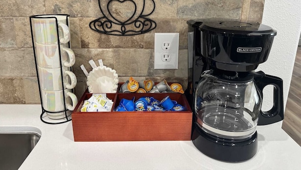 Una estación de café con cafetera, tazas y cápsulas de café.