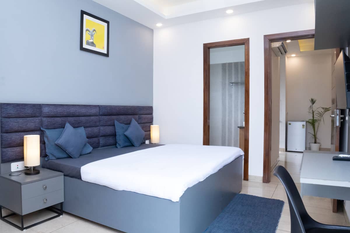 A modern bedroom with a large bed, bedside lamps, a desk, and a chair.
