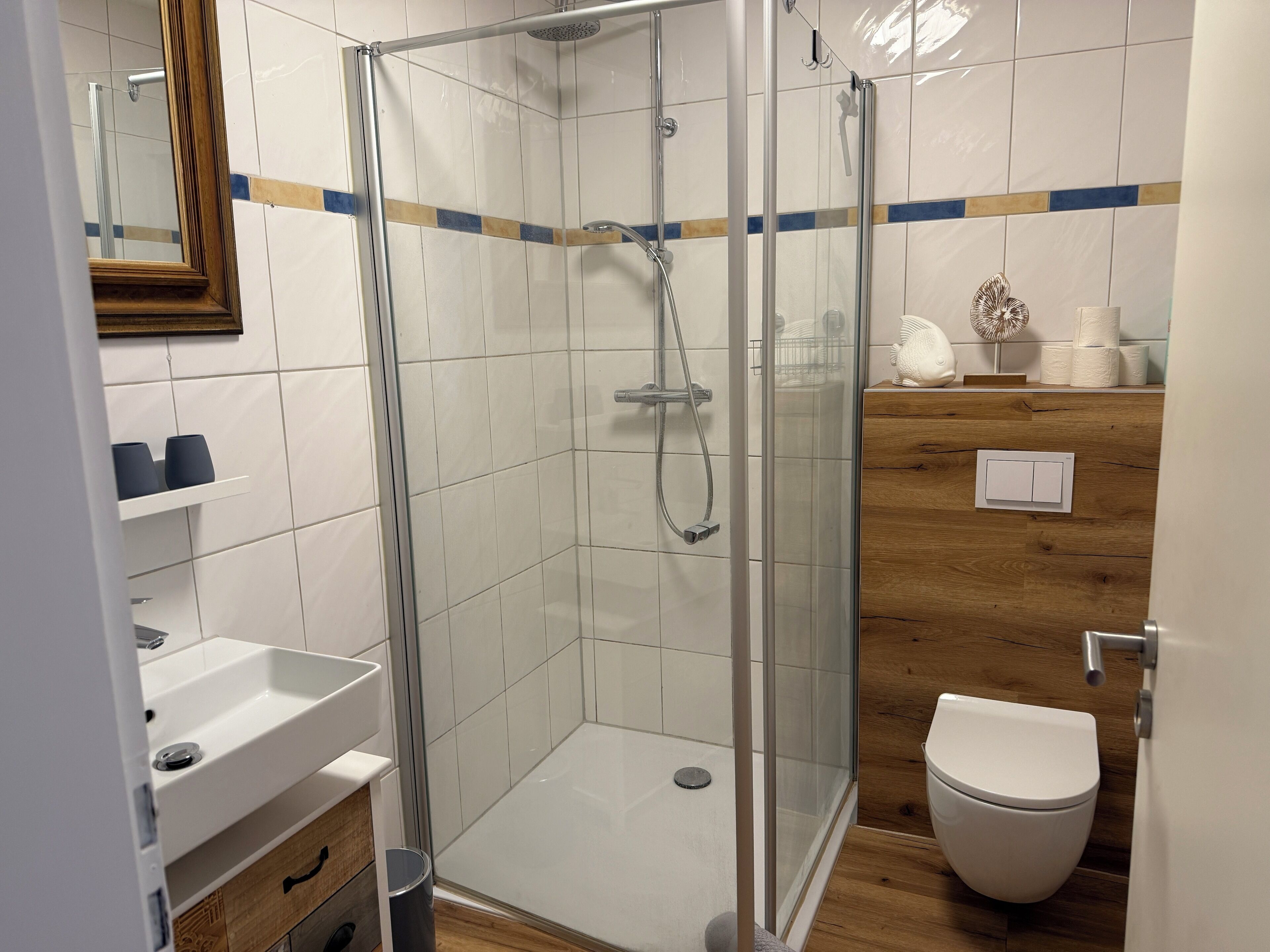 A modern bathroom with a glass-enclosed shower, a white sink, and a toilet.