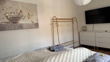 Quarto com uma cama, televisão, cômoda e um quadro na parede.