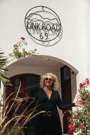 A person standing in front of a building with a sign that reads 'LINK ROAD 69'. - Frida, a 3-room apartment just a few minutes' walk from Blue Bay Lagoon. (Blue Bay)
