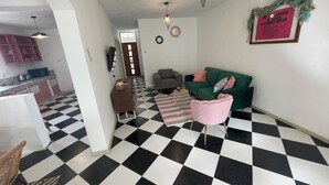 A living room with a checkered floor, a green sofa, a pink chair, and a small table. - Frida, 3-bedroom apartment just a few minutes' walk from Blue Bay lagoon. (Blue Bay)