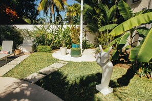 A garden with a statue, a white bench, and various plants. - Frida, a 3-room apartment just a few minutes' walk from Blue Bay Lagoon. (Blue Bay)
