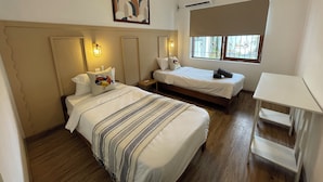 A hotel room with two beds, a ceiling fan, an air conditioning unit, a window with bars, and a small table. - Frida, 3-bedroom apartment just a few minutes' walk from Blue Bay lagoon. (Blue Bay)