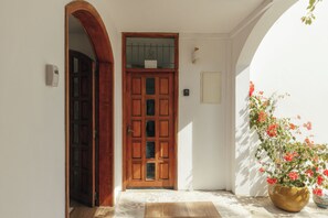 A wooden door with a window, a tiled floor, and a potted plant with red flowers. - Frida, a 3-room apartment just a few minutes' walk from Blue Bay Lagoon. (Blue Bay)