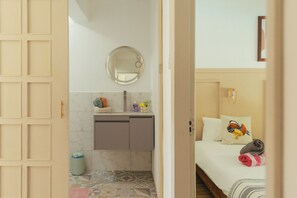 A compact room with a bed, a small bedside table, a mirror, and a bathroom with a toilet and sink. - Frida, a 3-room apartment just a few minutes' walk from Blue Bay Lagoon. (Blue Bay)