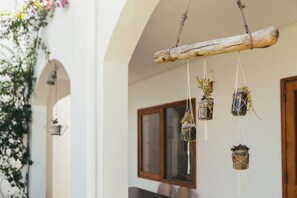 A rustic outdoor setting with a wooden beam suspended above, holding hanging planters with greenery. - Frida, a 3-room apartment just a few minutes' walk from Blue Bay Lagoon. (Blue Bay)