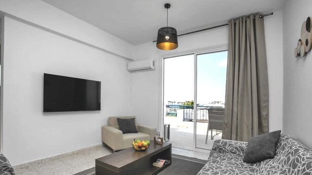 A modern living room with a sofa, a coffee table with fruit, a TV, and a balcony with a view. - Horizon-Amazing location & Seaview! (Latchi)