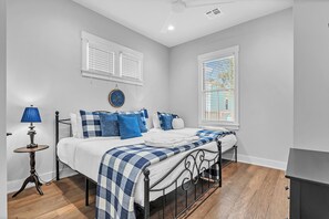 A bedroom with a bed, a bedside table, a lamp, and a window with blinds.