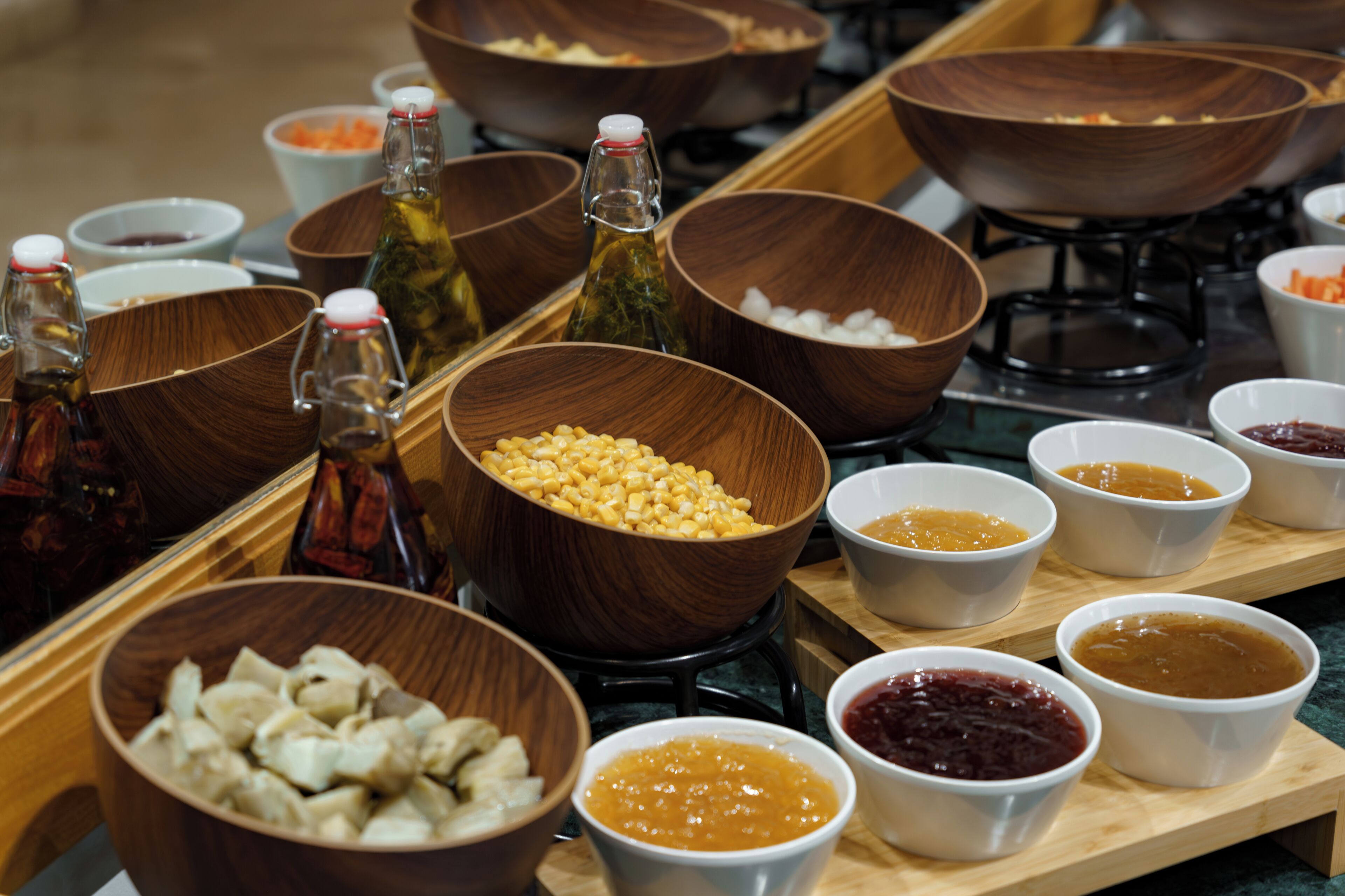 Una mesa de buffet con diversos alimentos y condimentos en cuencos y botellas.