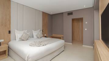 Un dormitorio moderno con una cama grande, paneles de madera, una mesita de noche y una televisión empotrada.