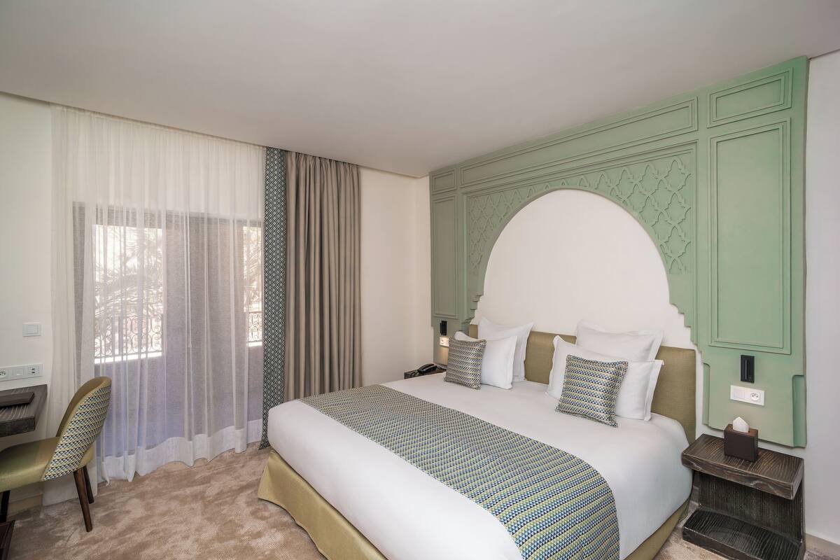 Une chambre d’hôtel avec un grand lit, un bureau et une chaise.