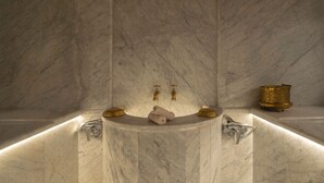 A marble bathroom with a built-in bathtub, two gold faucets, and a gold container on the side. - AMANAR Ouarzazate Boutique Hôtel & SPA  (Ouarzazate)