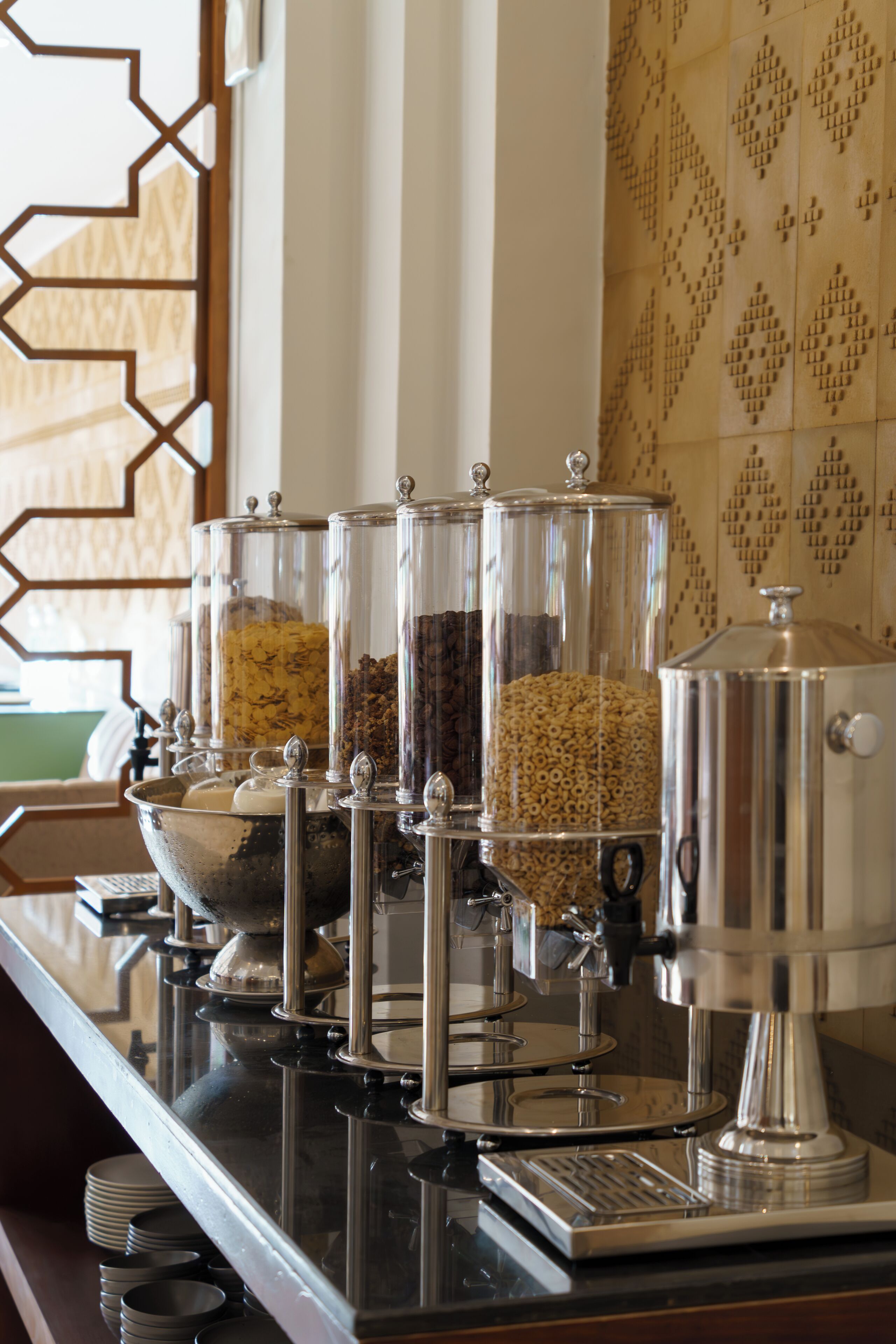 Una estación de café con una cafetera, un bol y varios recipientes de vidrio con diferentes alimentos.