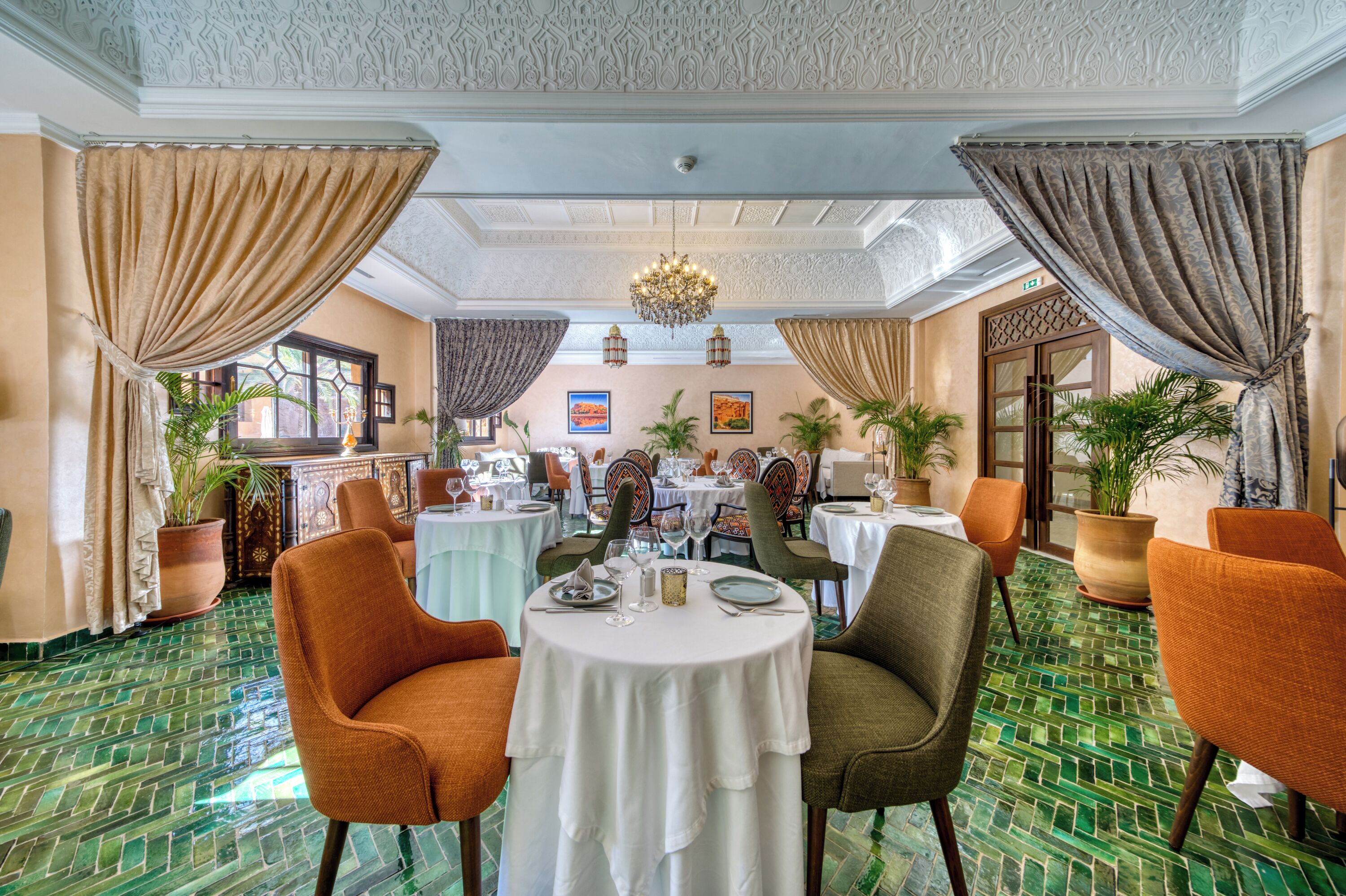 Un comedor con mesas redondas, sillas y plantas en macetas.