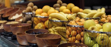 Un bufé con diversas opciones de comida, como frutas, frutos secos y productos de repostería.