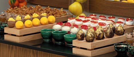 Un bufé con diversos alimentos, entre ellos frutas, pasteles y postres.