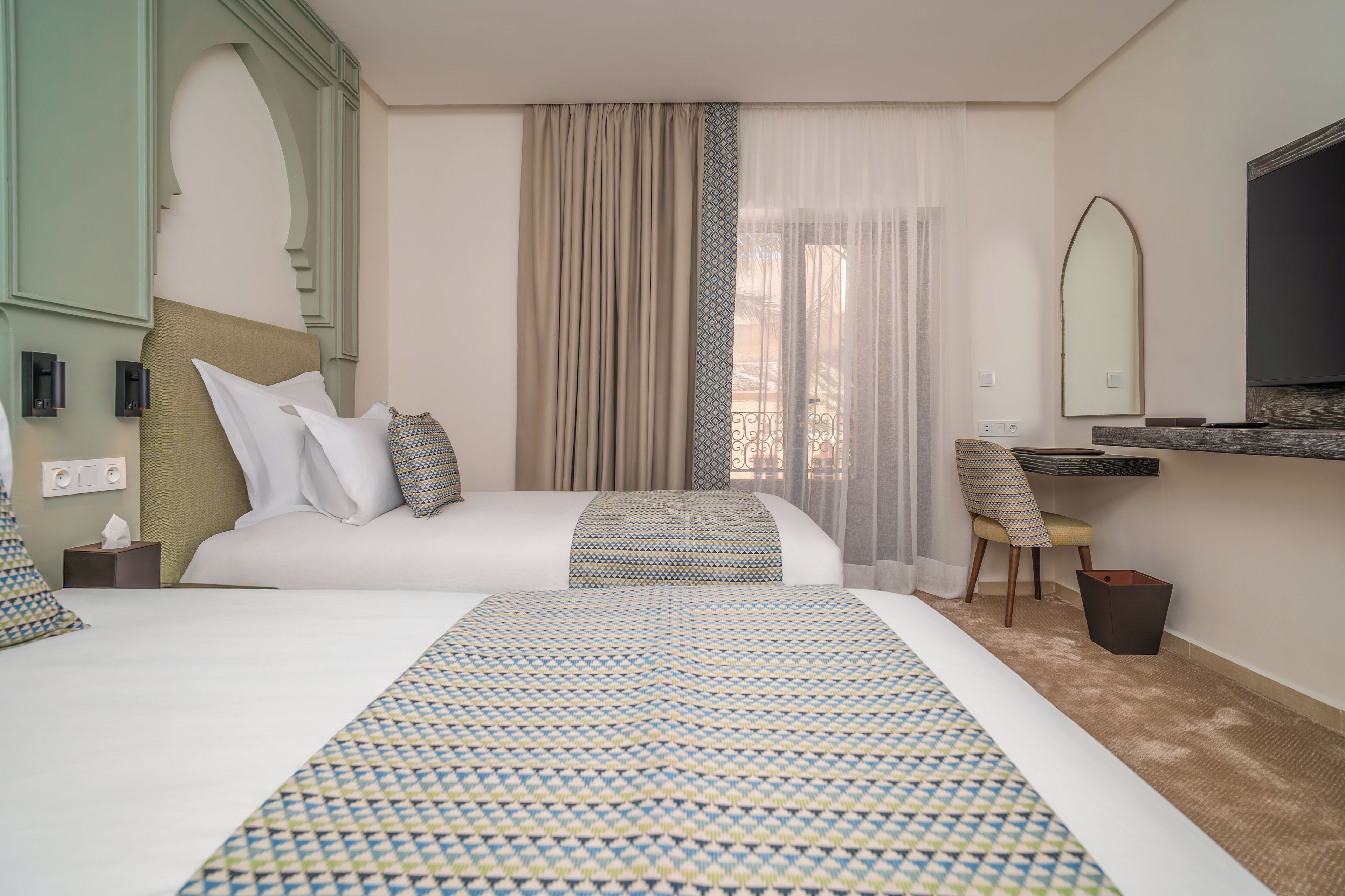 Habitación de hotel con dos camas, un escritorio, una silla, un televisor y un espejo.