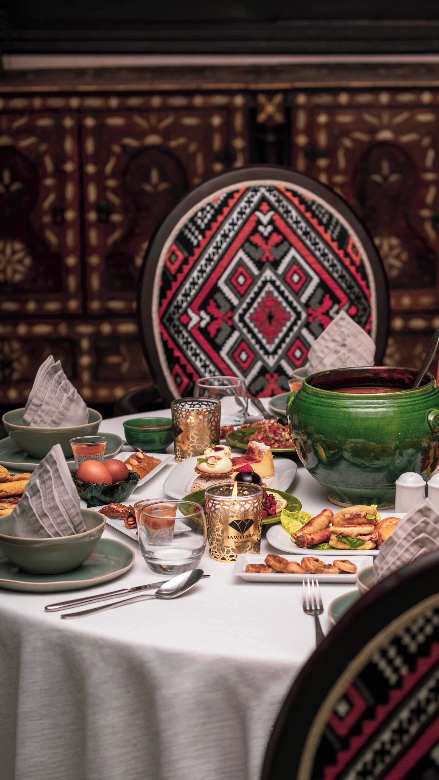 Une table à manger avec différents plats, une bougie et une chaise décorative.