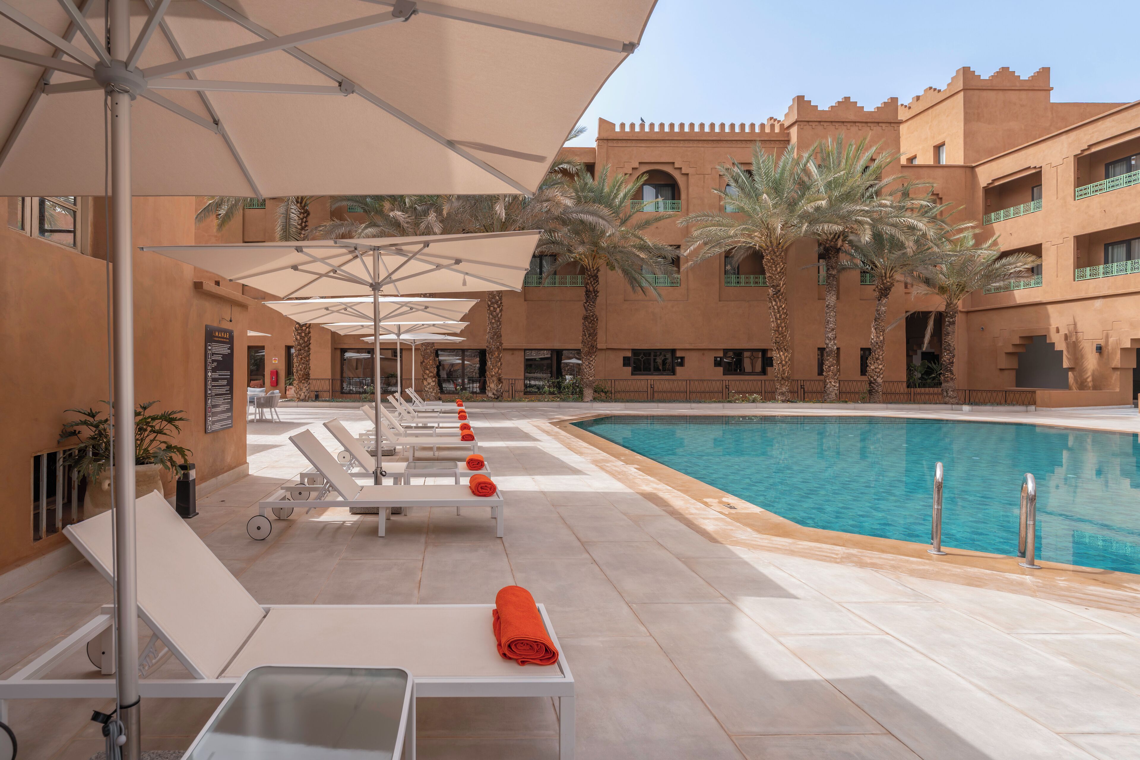 A poolside area with lounge chairs, umbrellas, and a pool.