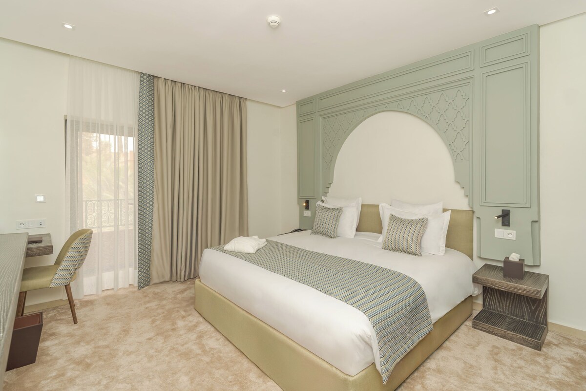 A hotel room with a large bed, a desk, and a chair.