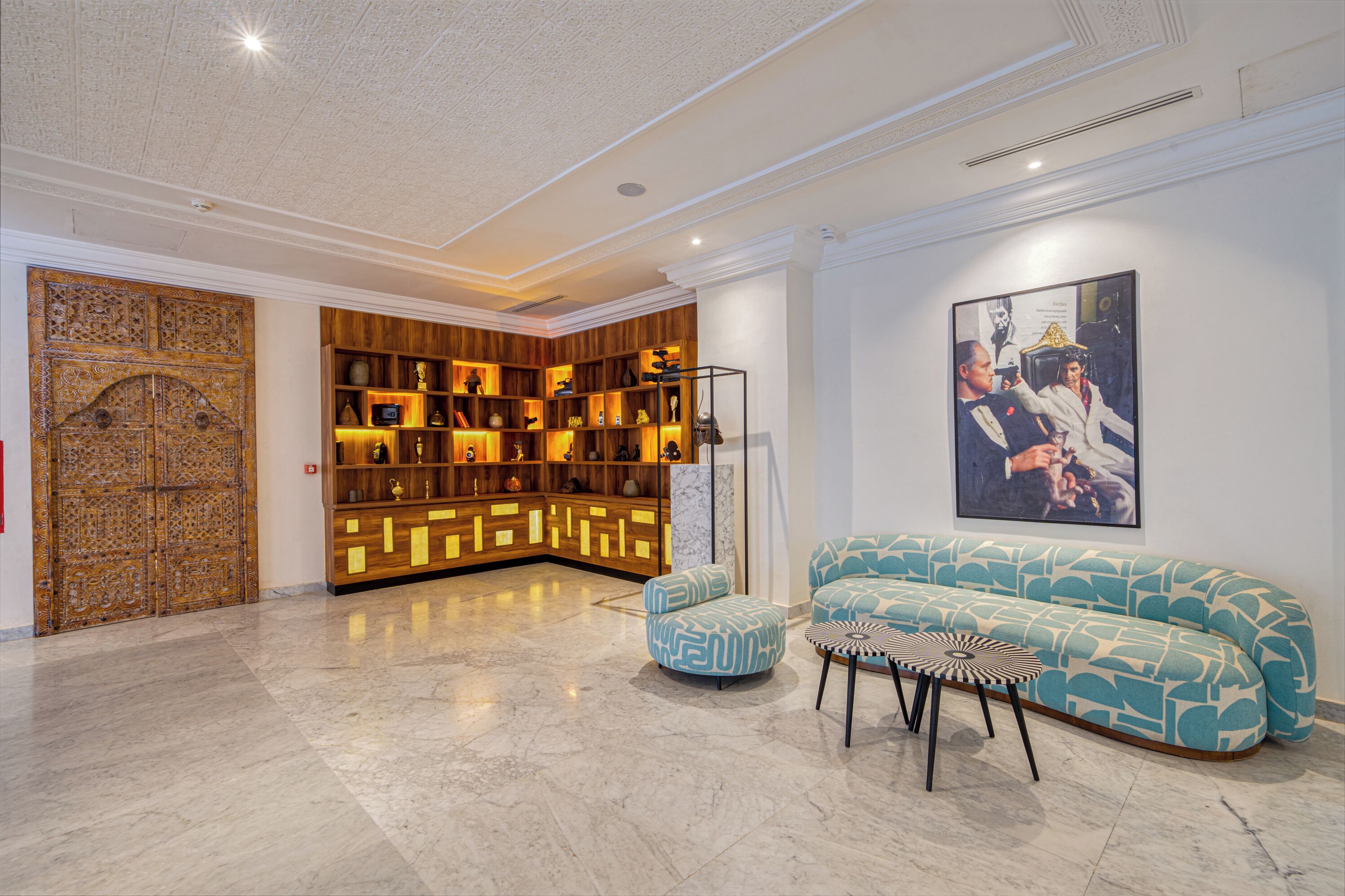 A lobby with a wooden cabinet, a blue sofa, and a framed picture on the wall.