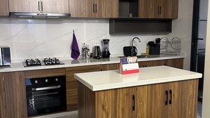 Une cuisine moderne avec des meubles en bois, un four encastré, une cuisinière à gaz et une machine à café.