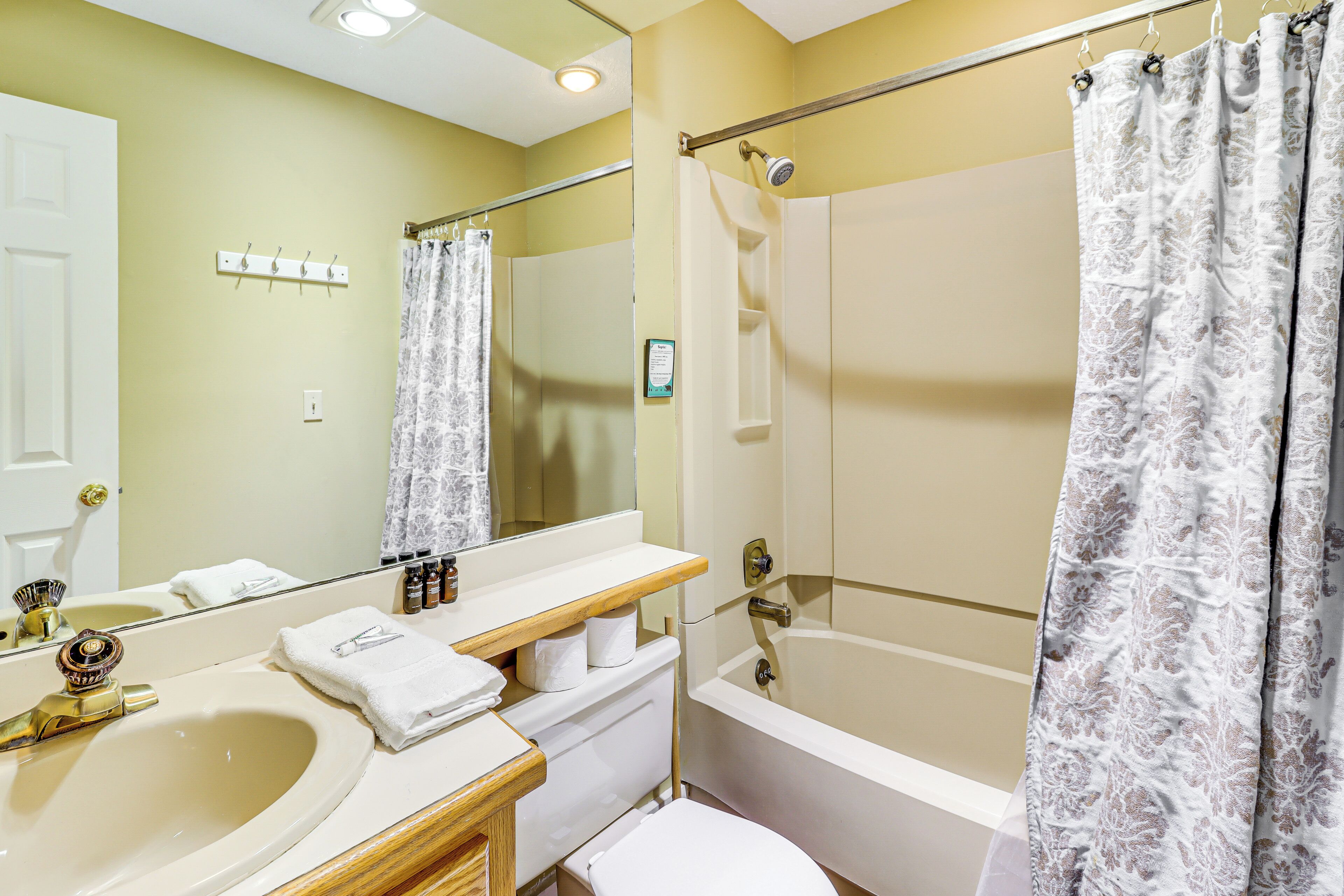 A bathroom with a sink, mirror, toilet, and bathtub.