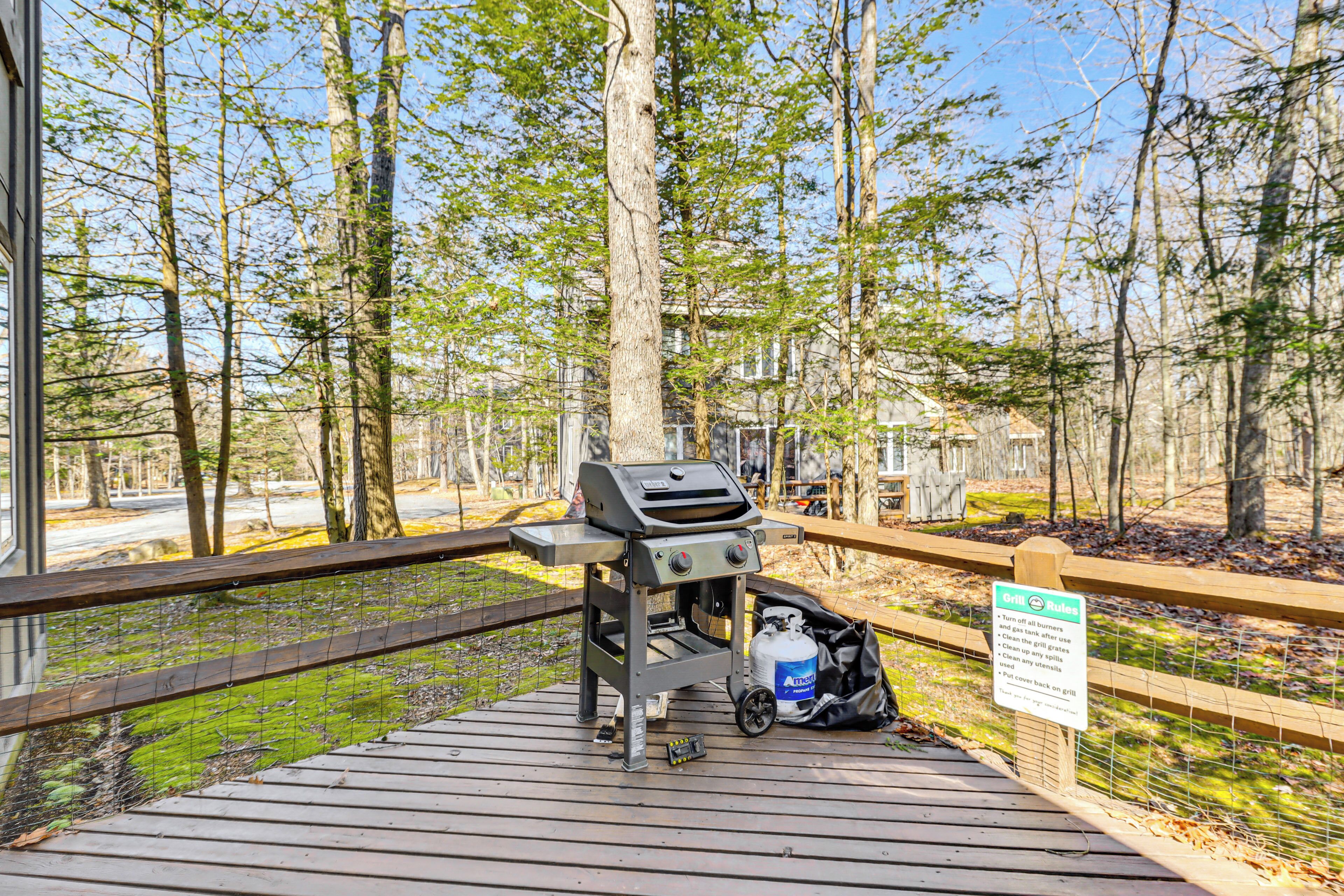 A portable grill on a wooden deck with a sign detailing its usage rules.