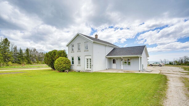 A two-story white house with a garage, surrounded by a well-maintained lawn and a gravel driveway. - Pet Friendly Home on 15 Acres - Lake Michigan (Manitowoc)