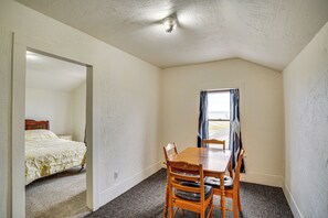 A bedroom with a wooden bed, a small dining table with chairs, and a window with curtains. - Pet Friendly Home on 15 Acres - Lake Michigan (Manitowoc)