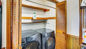 A laundry room with a washing machine and dryer, wooden shelves, and a door with a window. - Pet Friendly Home on 15 Acres - Lake Michigan (Manitowoc)