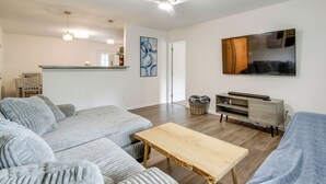 A modern living room with a grey sofa, a wooden coffee table, and a flat-screen TV mounted on the wall. - Commuter-friendly Home: 3 Mi to Dtwn Knoxville! (Knoxville)
