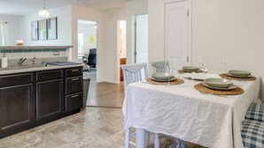 A modern kitchen with dark cabinetry, a granite countertop, and a white dining table set with green plates and wine glasses. - Commuter-friendly Home: 3 Mi to Dtwn Knoxville! (Knoxville)