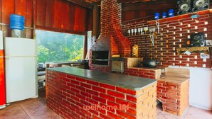 Une cuisine dotée d’un îlot central en briques, d’un four encastré et d’un intérieur au style rustique, avec des éléments en bois.