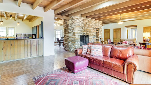A spacious living area with a stone fireplace, leather sofas, and wooden beams on the ceiling. - 3 Mi to Zoo & Garden: ABQ Home w/ Private Pool! (Albuquerque)