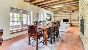 A spacious dining area with a wooden table and chairs, large windows, and a stone wall. - 3 Mi to Zoo & Garden: ABQ Home w/ Private Pool! (Albuquerque)