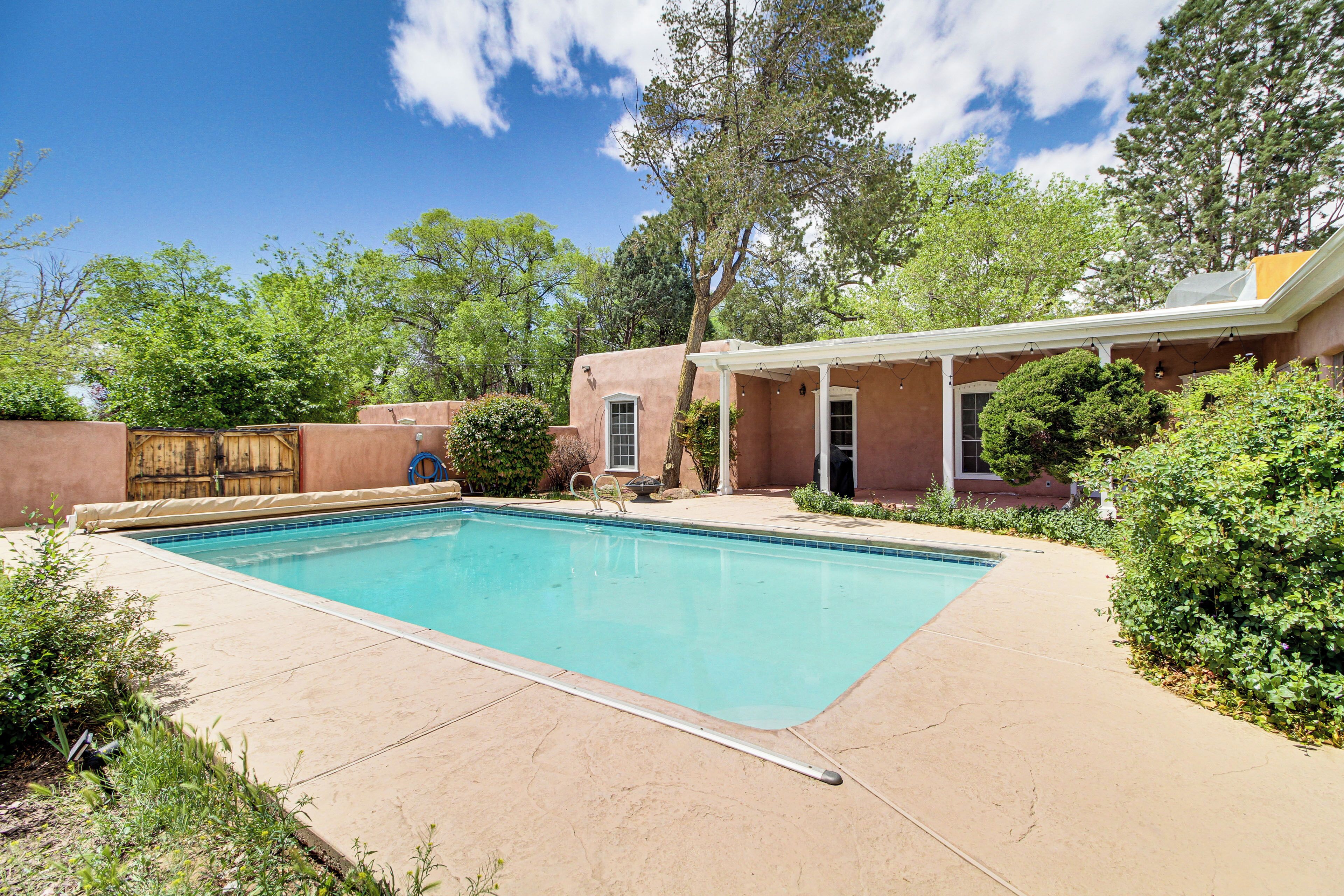A rectangular swimming pool with a clear blue water surface, surrounded by a beige patio area.