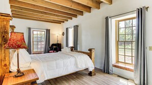 A bedroom with a wooden bed, a nightstand, a lamp, and a window with curtains. - 3 Mi to Zoo & Garden: ABQ Home w/ Private Pool! (Albuquerque)