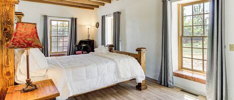 Un dormitorio con una cama de madera, una mesita de noche, una lámpara y una ventana con cortinas.