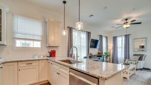 Una cocina moderna con armarios blancos, encimeras de granito, lavavajillas integrado y una isla central.