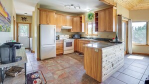 A kitchen with wooden cabinets, a refrigerator, stove, microwave, and a window with curtains. - Hunt, Fish & Explore: Mtn-view Home in Hotchkiss (Hotchkiss)