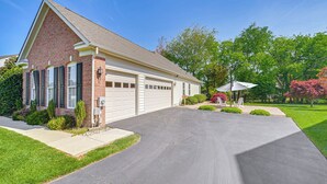 Une maison à deux étages avec un garage, une allée et une pelouse bien entretenue.