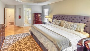 Une chambre à coucher avec un grand lit, un ventilateur de plafond, une commode et une table de chevet.