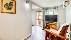 Un couloir avec un banc en bois, un téléviseur posé sur un meuble en bois et un tableau encadré accroché au mur.