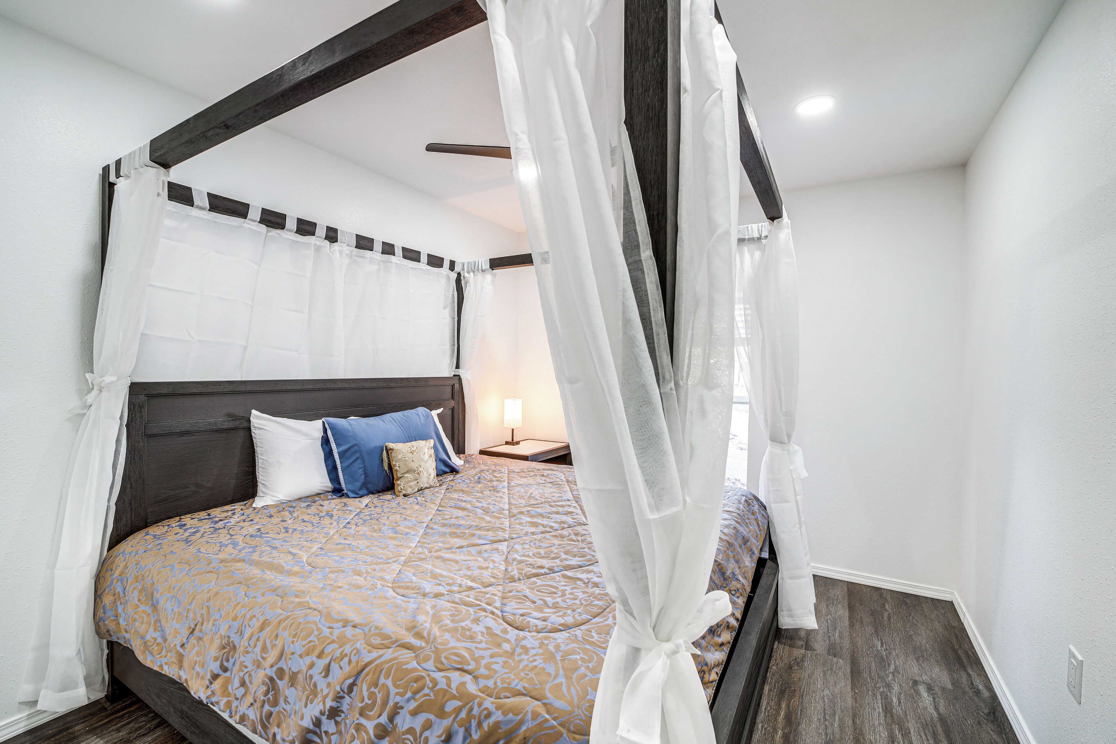 Une chambre à coucher avec un lit à baldaquin, un ciel de lit, une table de chevet et une lampe de chevet.